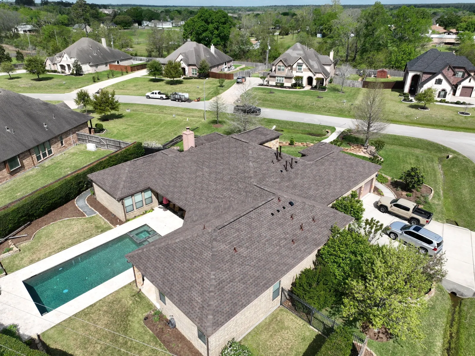 Aerial view of a finished brown shingle roof on a one-story home with a pool
